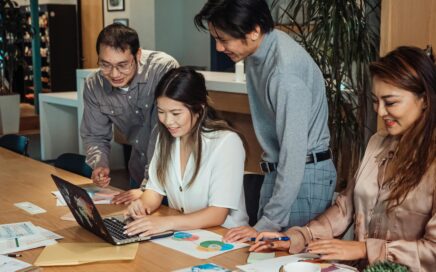 Professionals discussing ideas during an office meeting with laptops, papers, and charts
