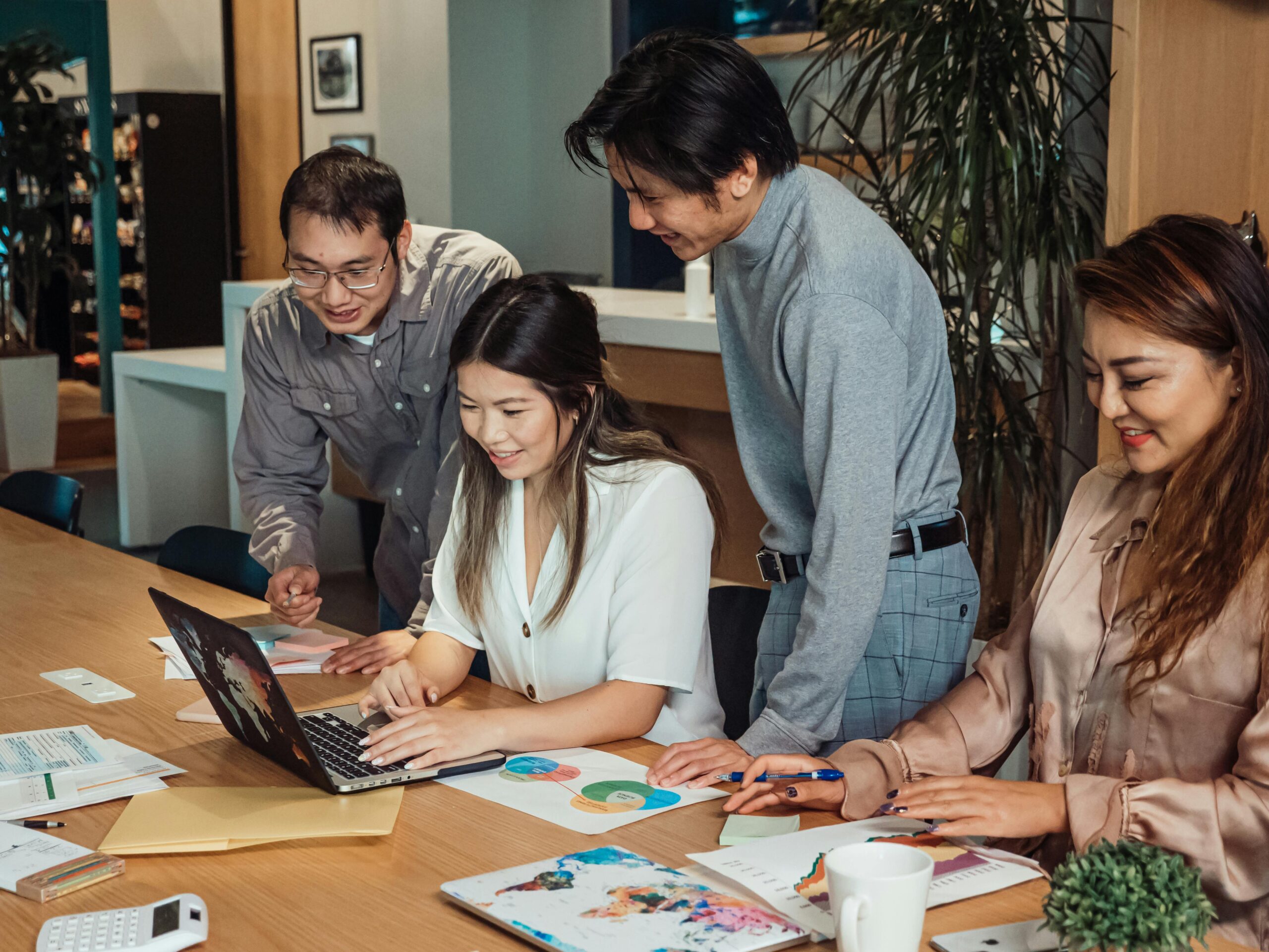 Professionals discussing ideas during an office meeting with laptops, papers, and charts