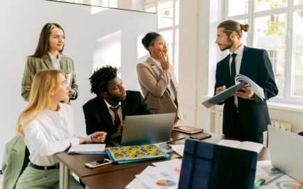 Group of professionals collaborating in a bright office space with laptops, documents, and charts