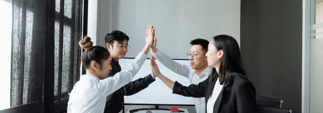 Smiling team members collaborate, shake hands, and discuss ideas in a modern workspace