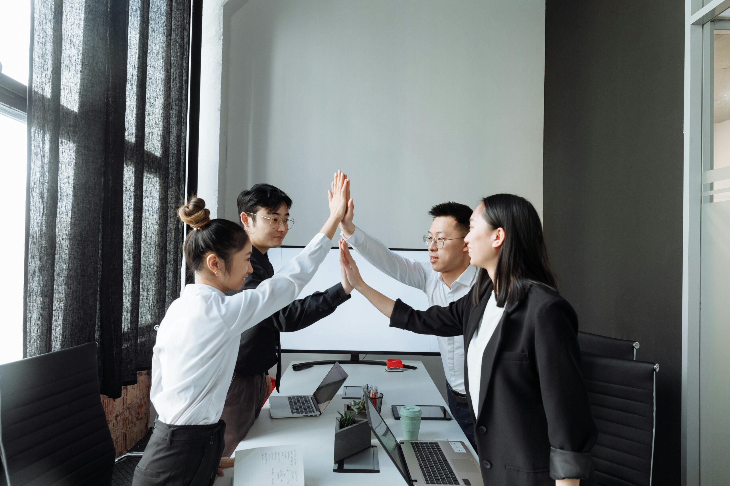 Smiling team members collaborate, shake hands, and discuss ideas in a modern workspace
