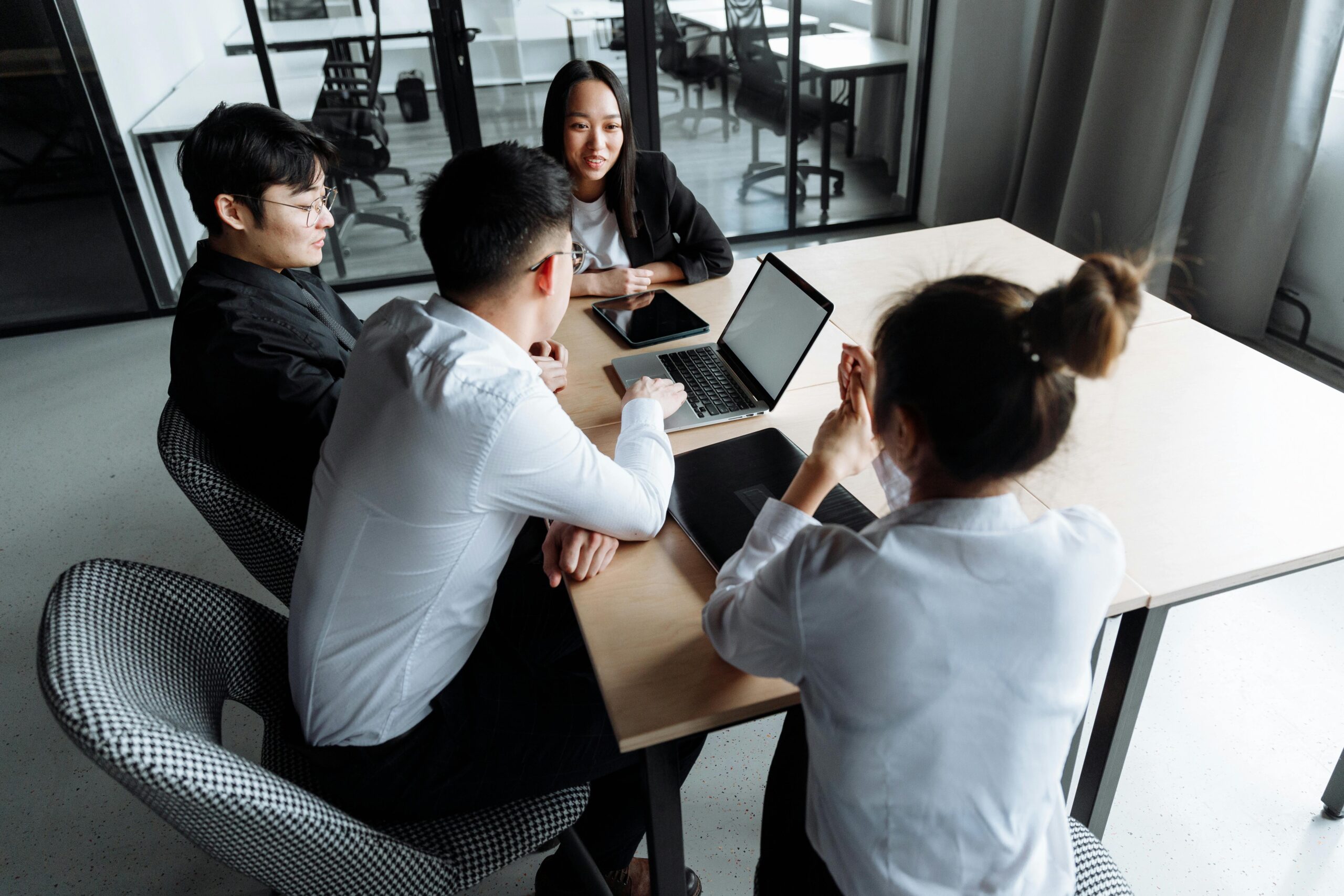 Business team working together around a table with laptops, documents, and open discussions