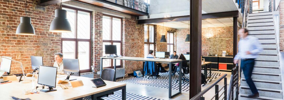 A modern coworking space with brick walls, open desks, and a bright, industrial-style interior.
