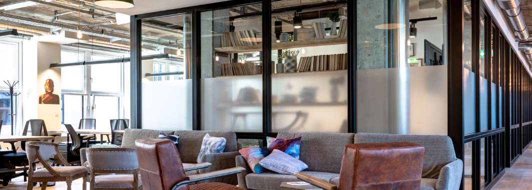 Stylish coworking lounge with vintage leather chairs, a sofa, and industrial-style ceiling and decor