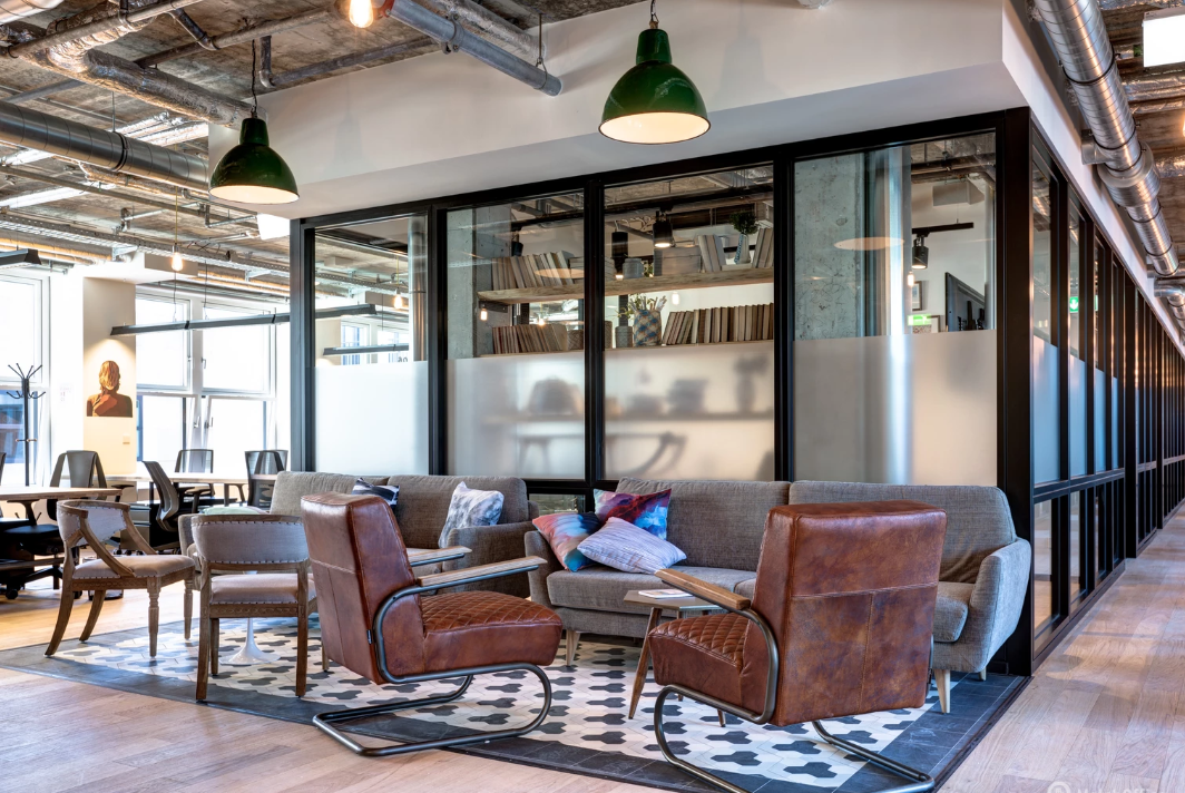Stylish coworking lounge with vintage leather chairs, a sofa, and industrial-style ceiling and decor