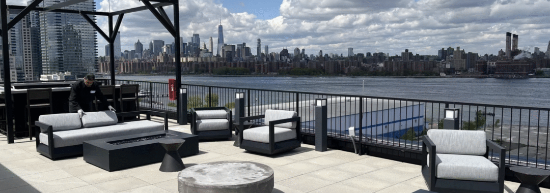 Rooftop office lounge with city skyline views, outdoor seating, and a modern fire pit.