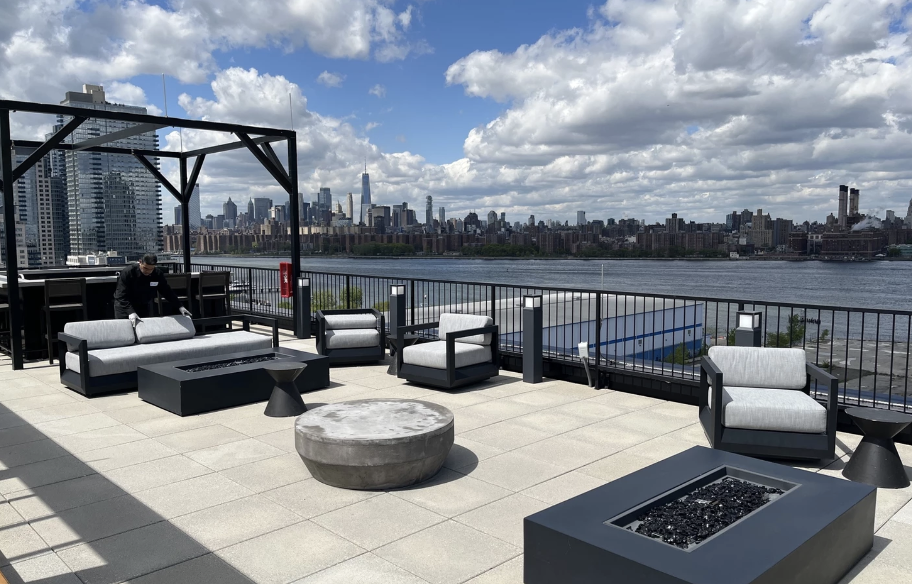 Rooftop office lounge with city skyline views, outdoor seating, and a modern fire pit.