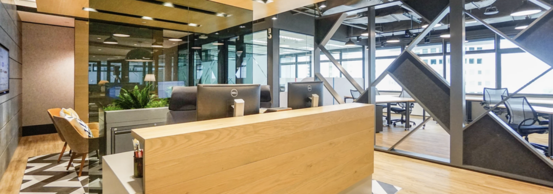 Modern coworking office reception with wooden design, open layout, and stylish black metal partitions